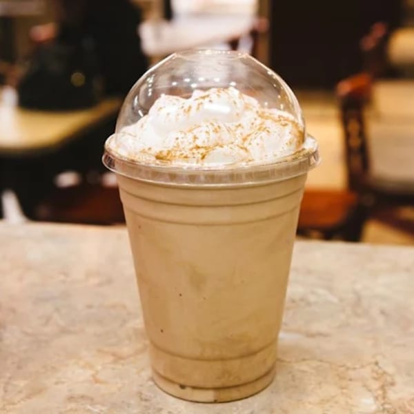 A Charley's Deli and Grille iced coffee with whipped cream and cinnamon in a plastic cup.