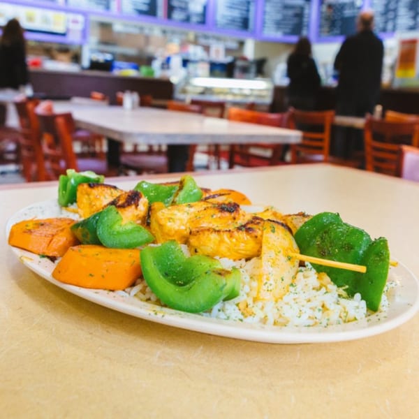 Chicken and green pepper skewers with rice and roasted sweet potatoes on a plate at Charley's Deli.