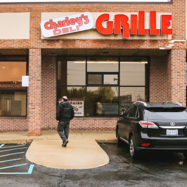 Exterior of Charley's Deli and Grille, a brick building with a black car parked outside.